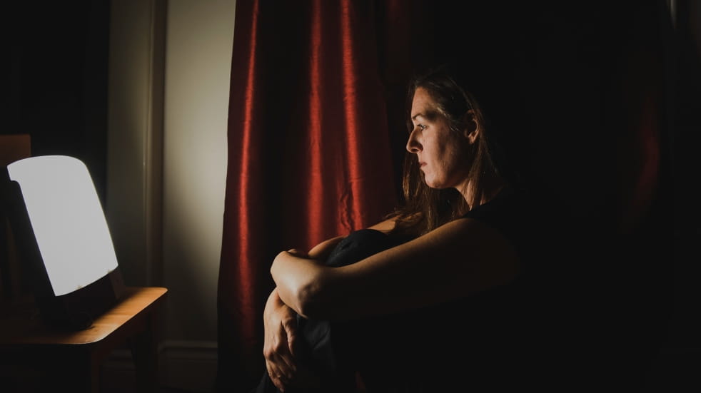 woman sitting beside daylight lamp